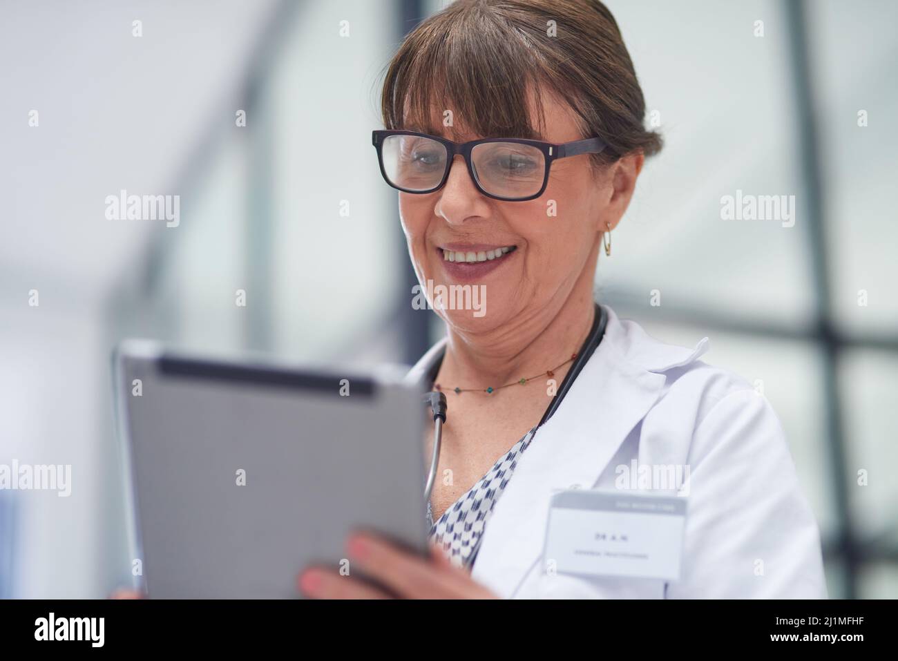 Live appointments have been a brilliant work around. Shot of a mature female doctor using a tablet. Stock Photo