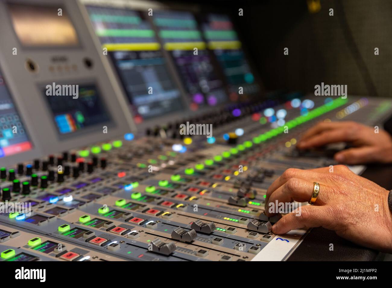 Hands mixing on a broadcast audio console for live television Stock