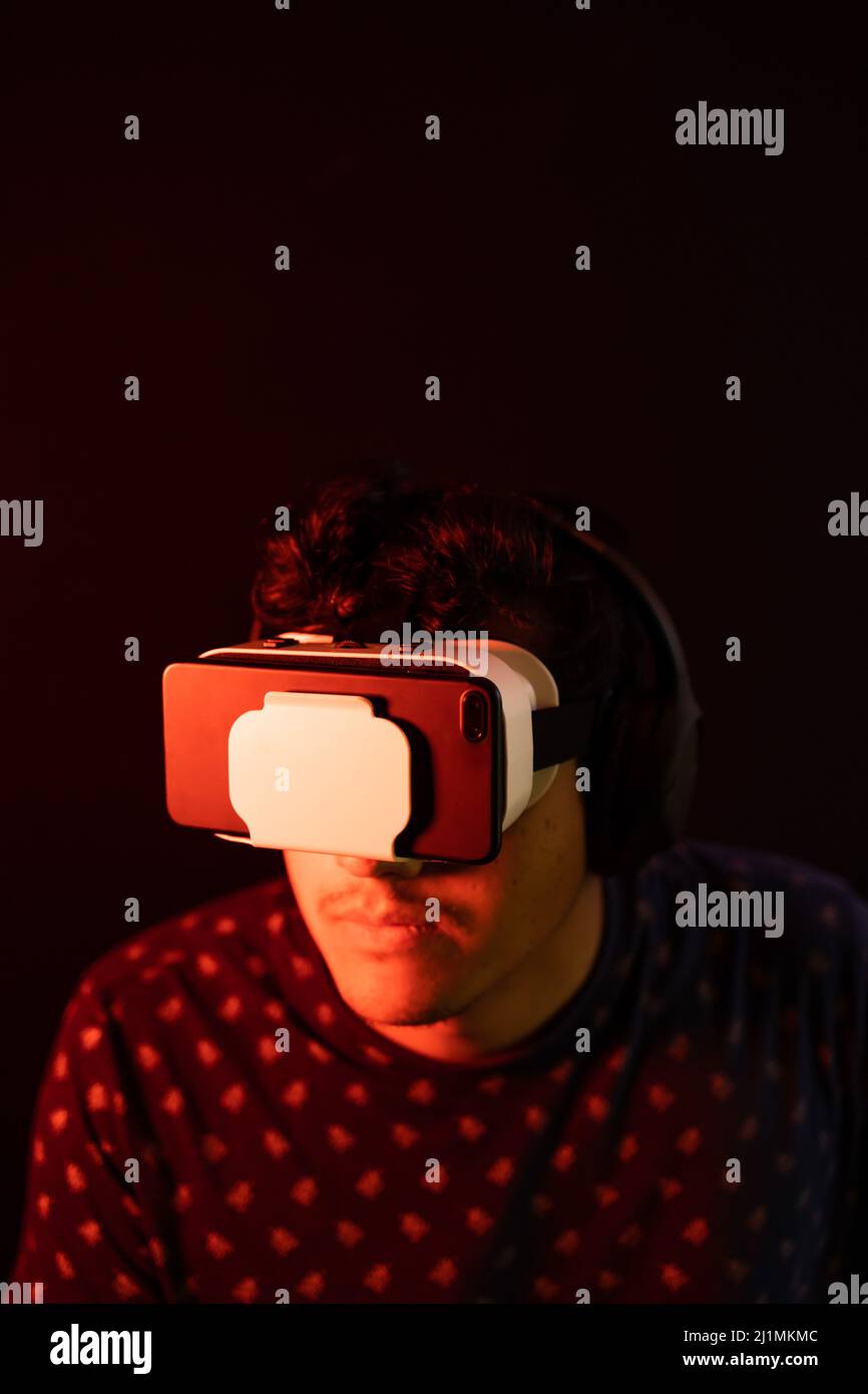 Young latin man using Virtual Reality VR Headset 3D Glasses. Dark backdrop. Low key. Copy space. Stock Photo