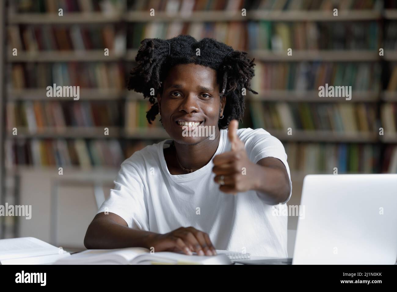 African student sit at desk in library showing thumbs up Stock Photo ...