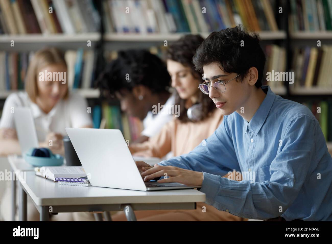 Student guy wear glasses studying in library using laptop Stock Photo