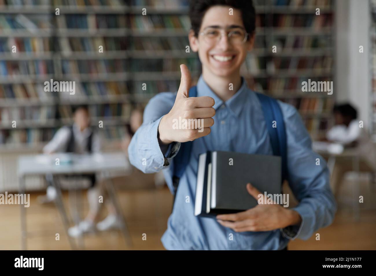 Student guy posing in library showing thumbs up at camera Stock Photo ...