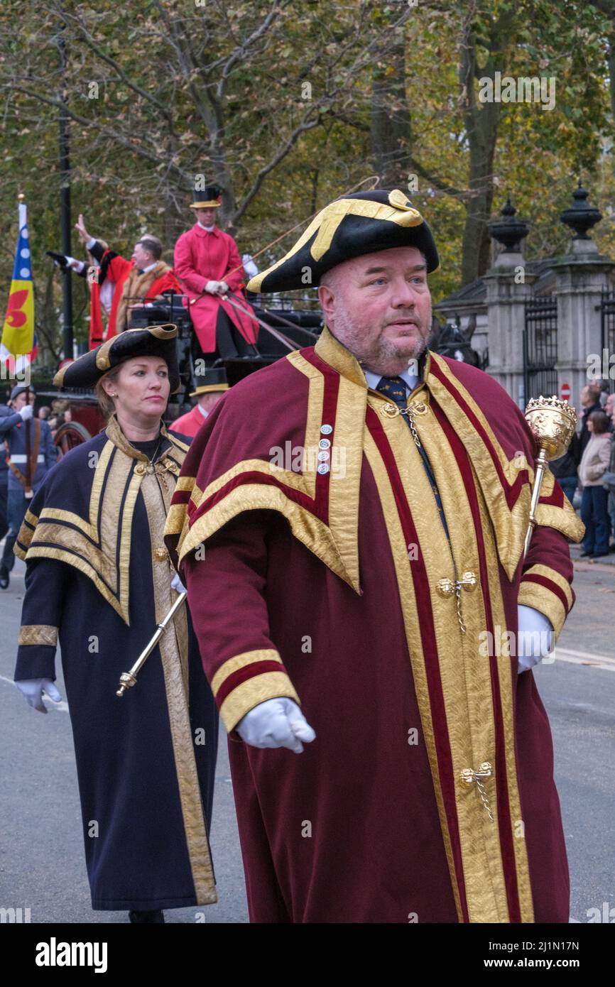 Man & woman dressed in ornate ceremonial robes & hats with gold trim