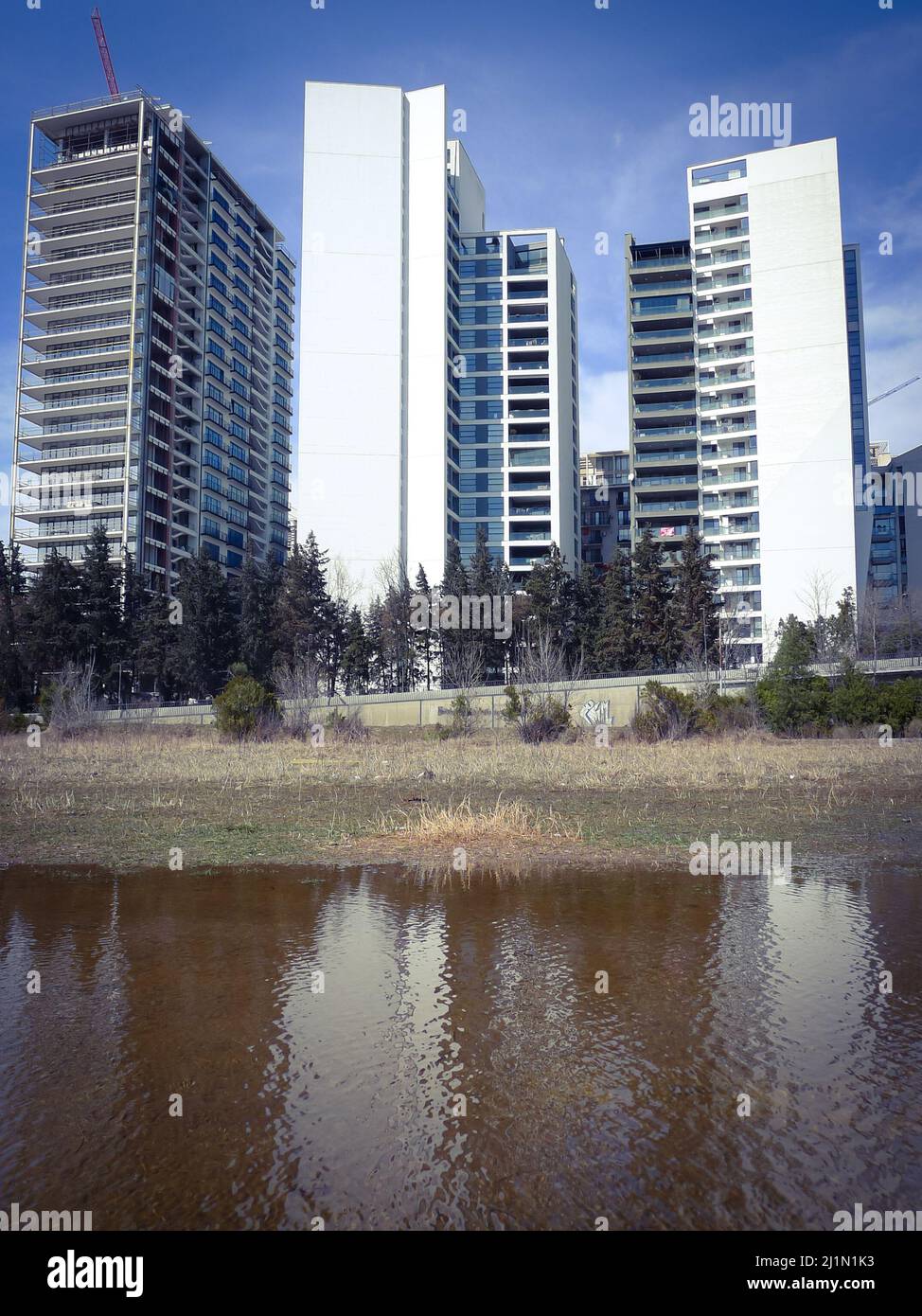 Modern multistory buildings reflected in water. Puddle with reflections. Stock Photo
