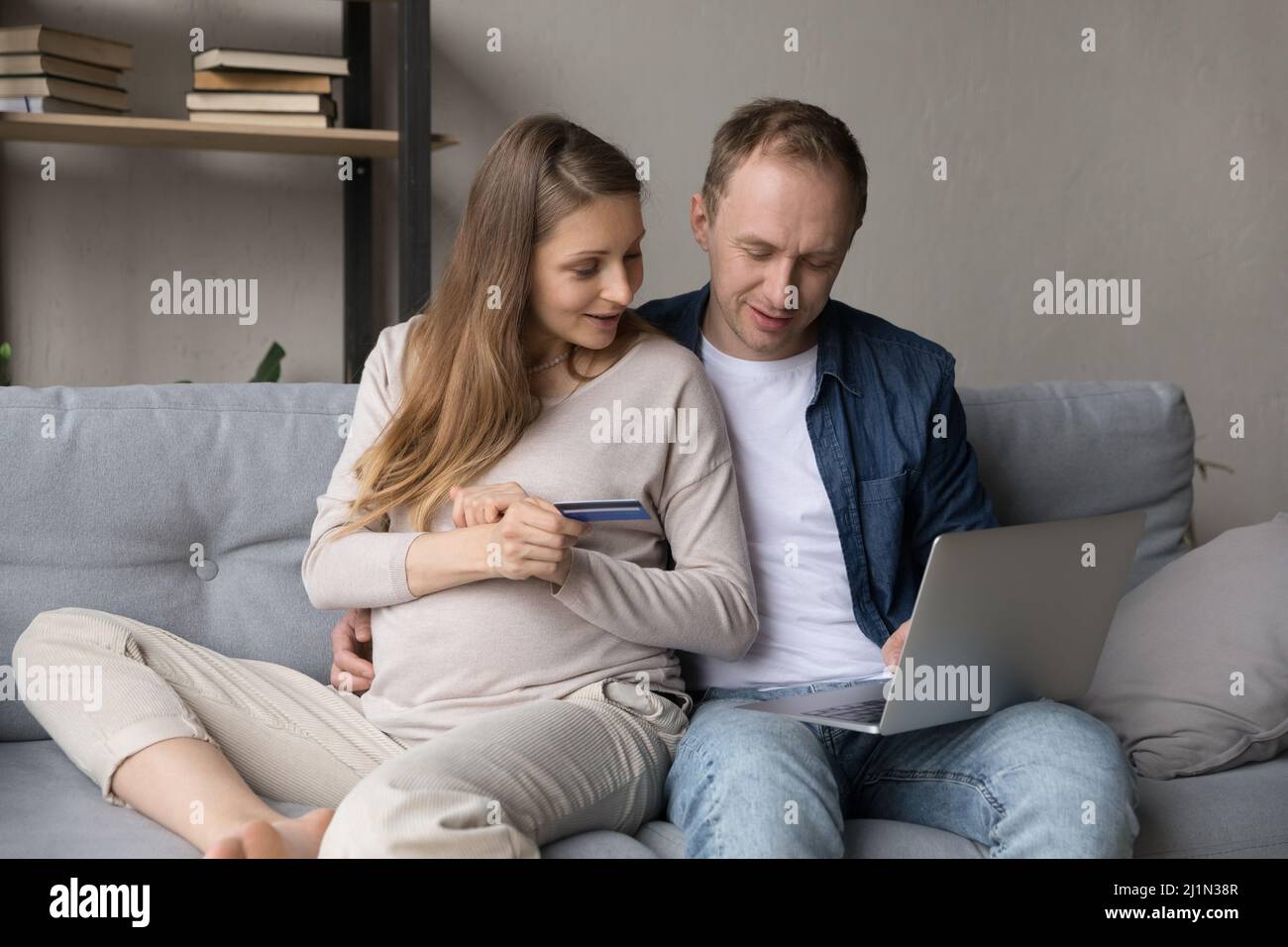 Happy young pregnant woman shopping with husband on computer. Stock Photo