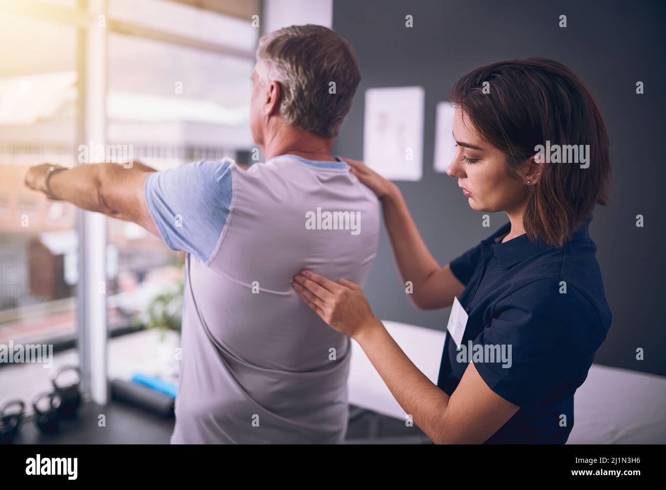 Just a little more. Cropped shot of a young female physiotherapist treating a mature male patient. Stock Photo