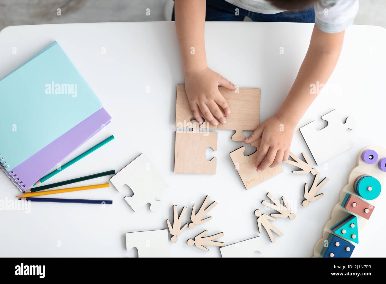 Top view hands of little child arranging wooden puzzles, symbol of public awareness for autism spectrum disorder Stock Photo