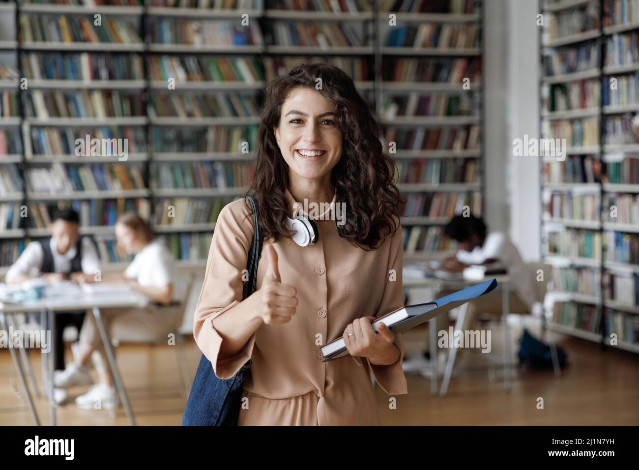 Attractive student girl standing in library showing thumbs up Stock ...