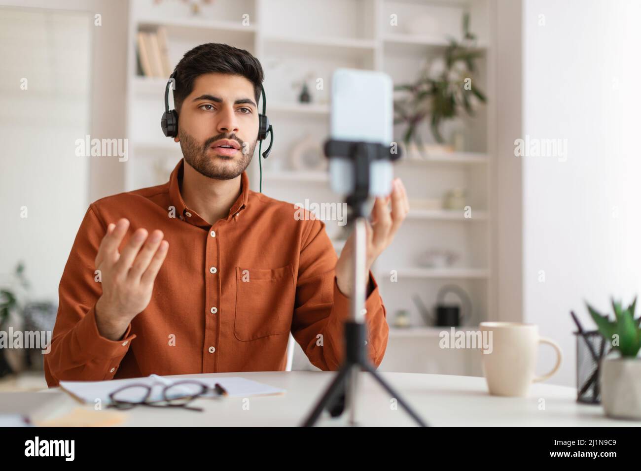 Arab man having videocall using cellphone on tripod Stock Photo
