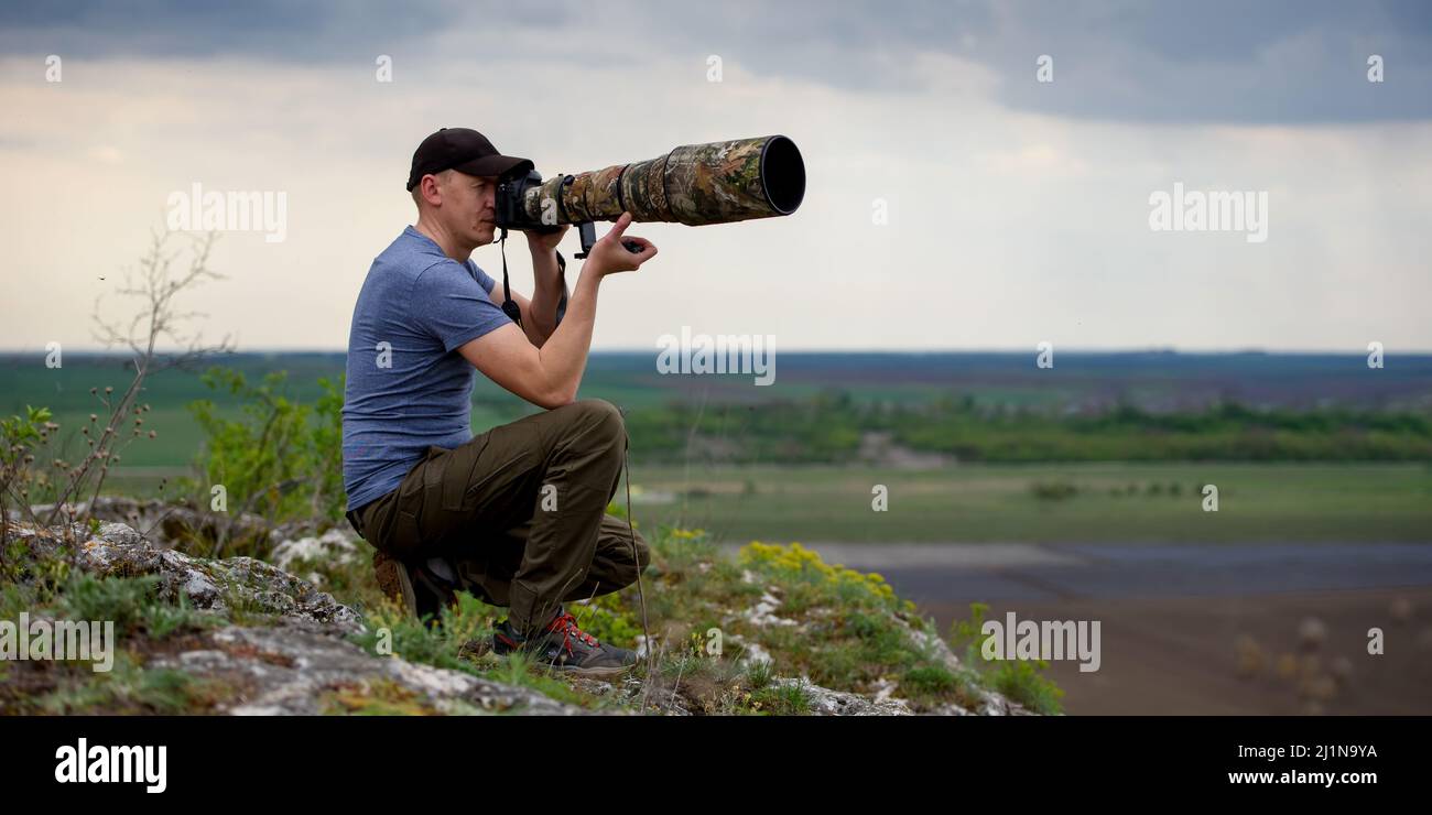 Wildlife photographer on big lake background in summer time working in the wild Stock Photo