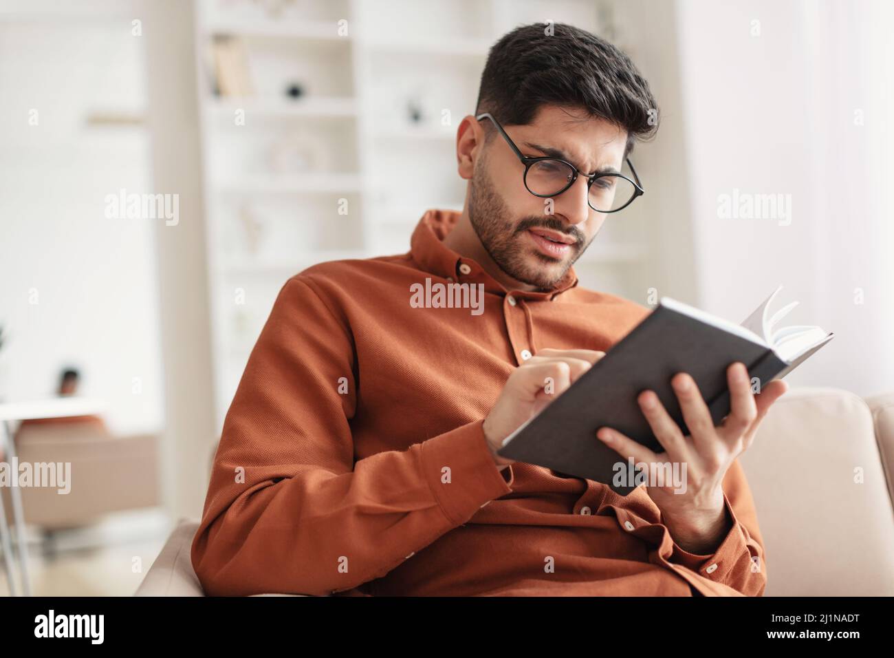 Focused Arab man in glasses trying to read book Stock Photo Alamy