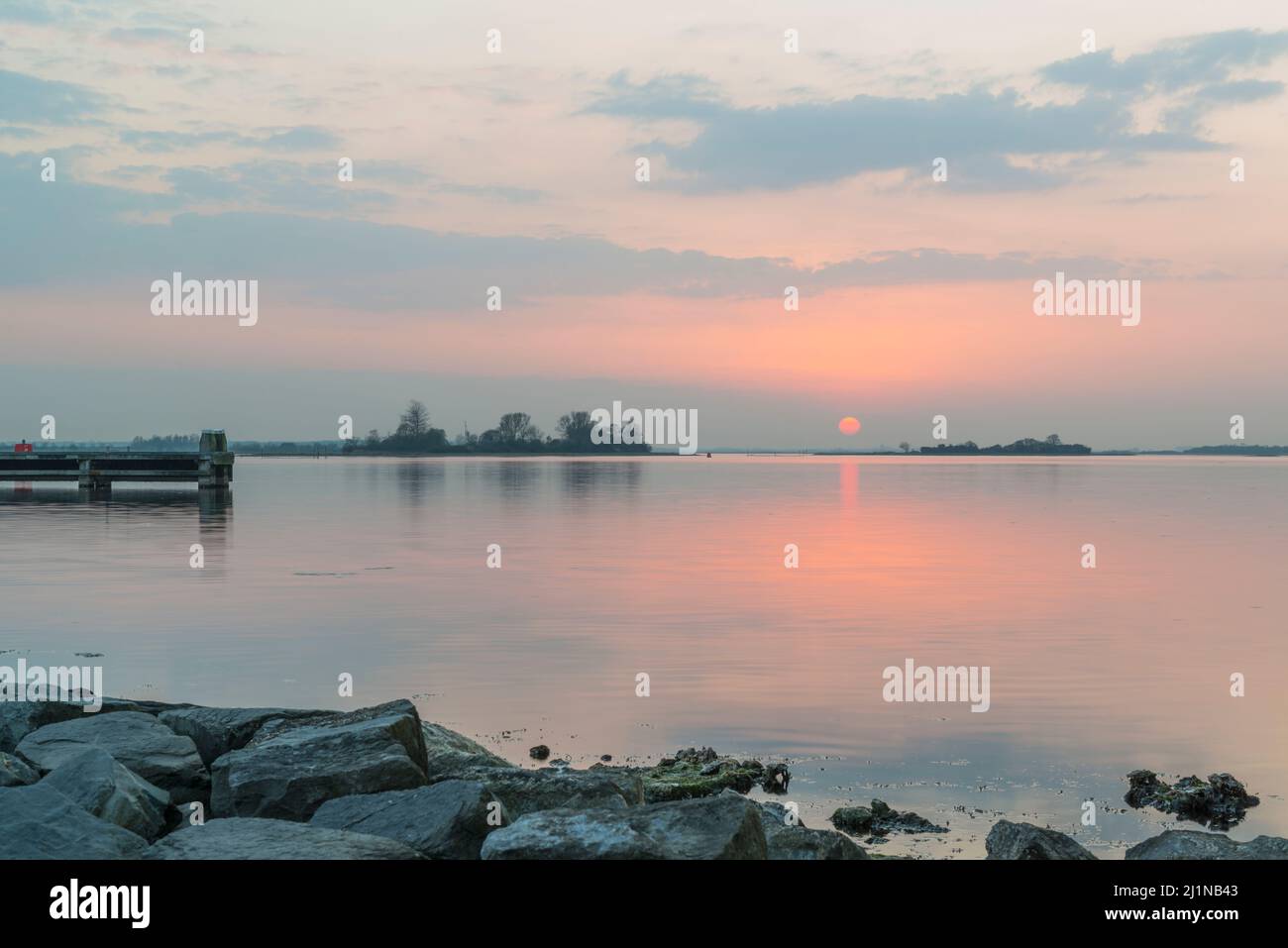 Sunset at the Veerse Meer with reflections in the almost placid lake. Zeeland, Netherlands Stock Photo