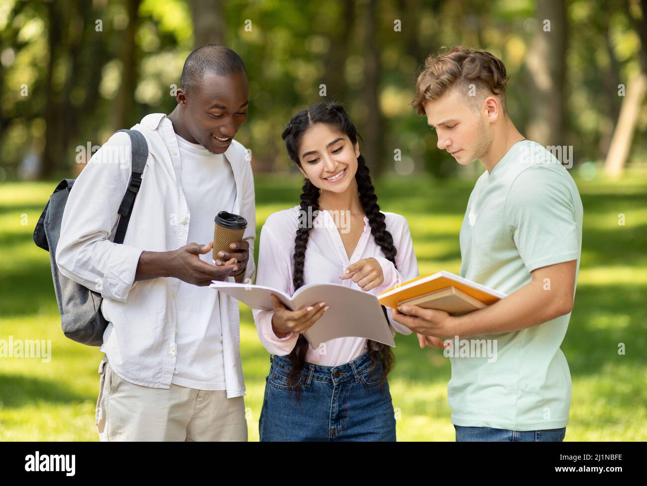 Diverse student friends going to college class, reading books and notepads outdoors, preparing for lecture or test Stock Photo