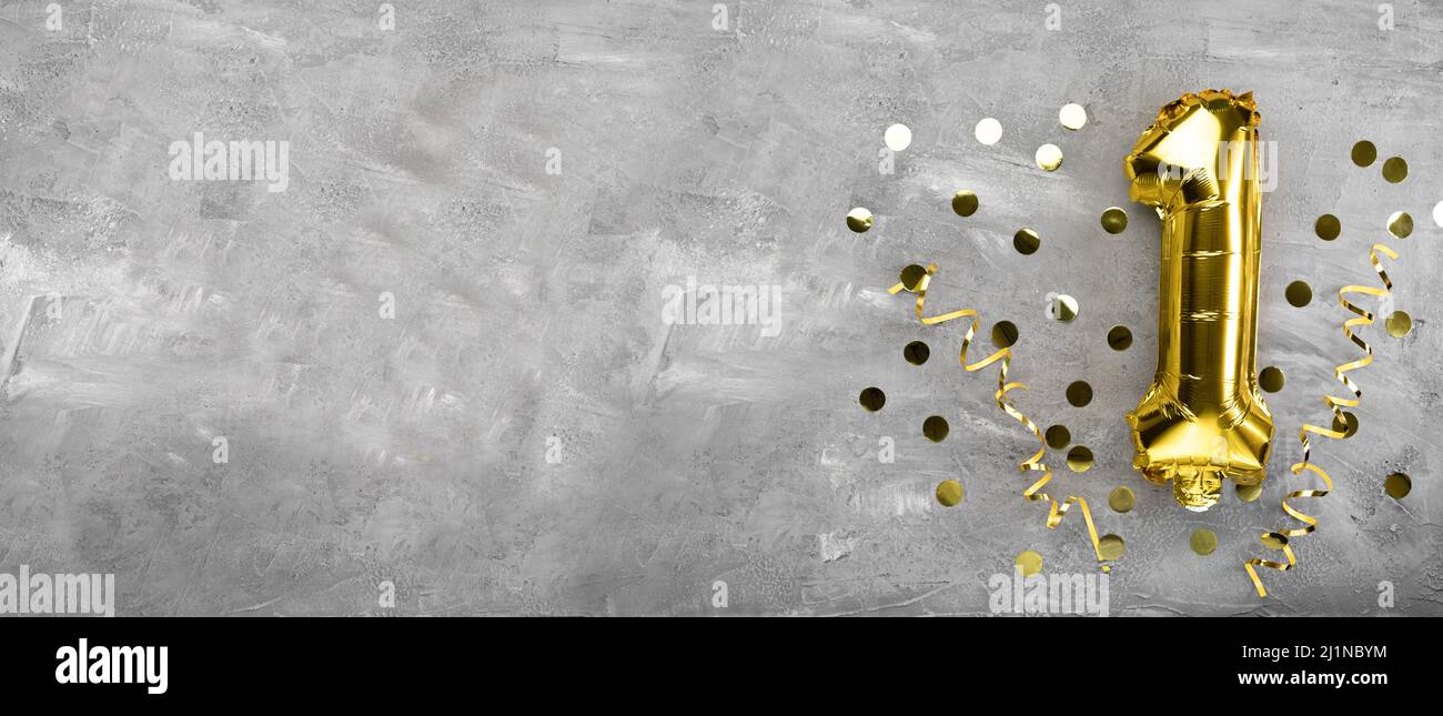 Yellow foil balloon number, number one on a concrete background