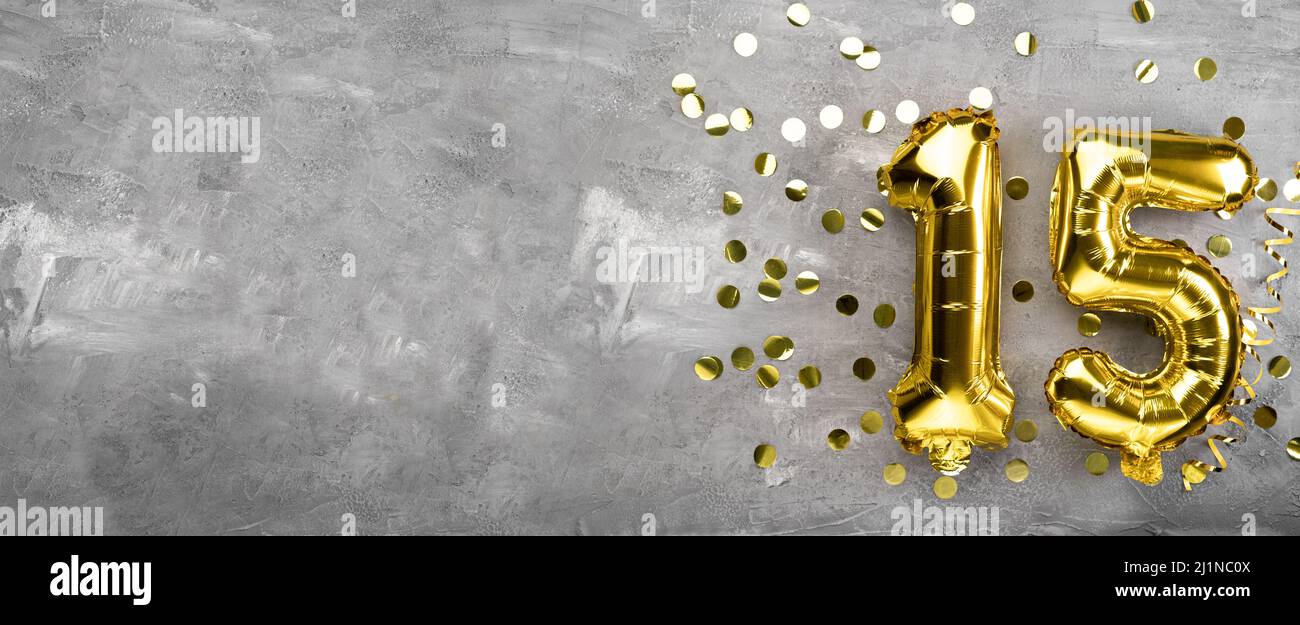 Yellow foil balloon number, number fifteen on a concrete background. 15th birthday card. Anniversary concept. for anniversary, birthday, new year Stock Photo