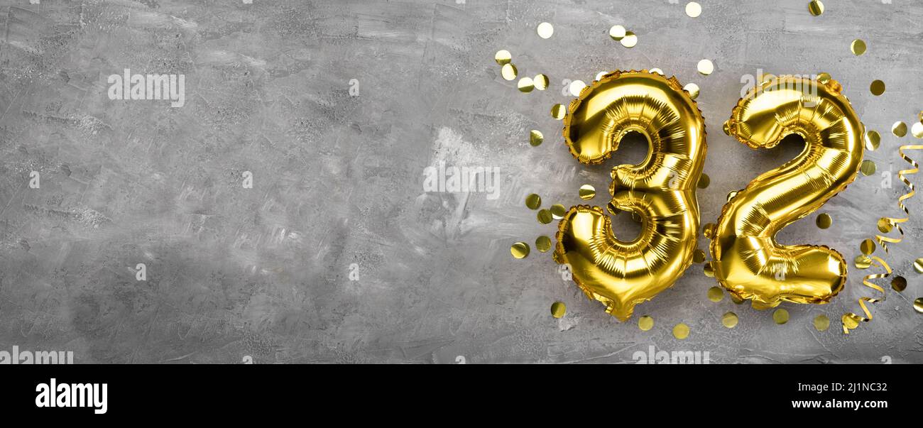 Yellow foil balloon number, number thirty-two on a concrete background. Birthday card with 32 inscription. Anniversary concept. for anniversary Stock Photo