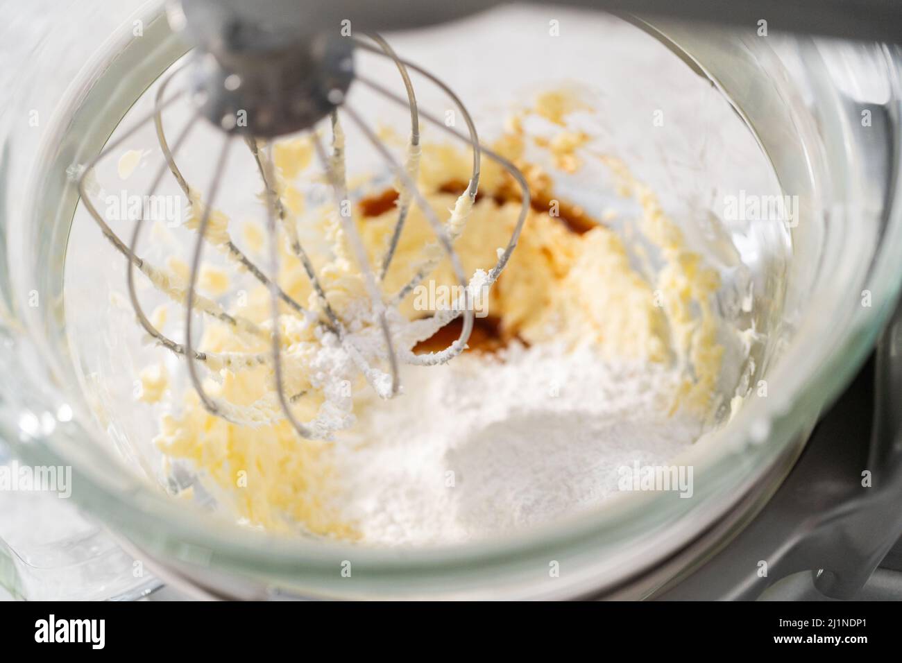 Whipping strawberry buttercream frosting in a standalone electric