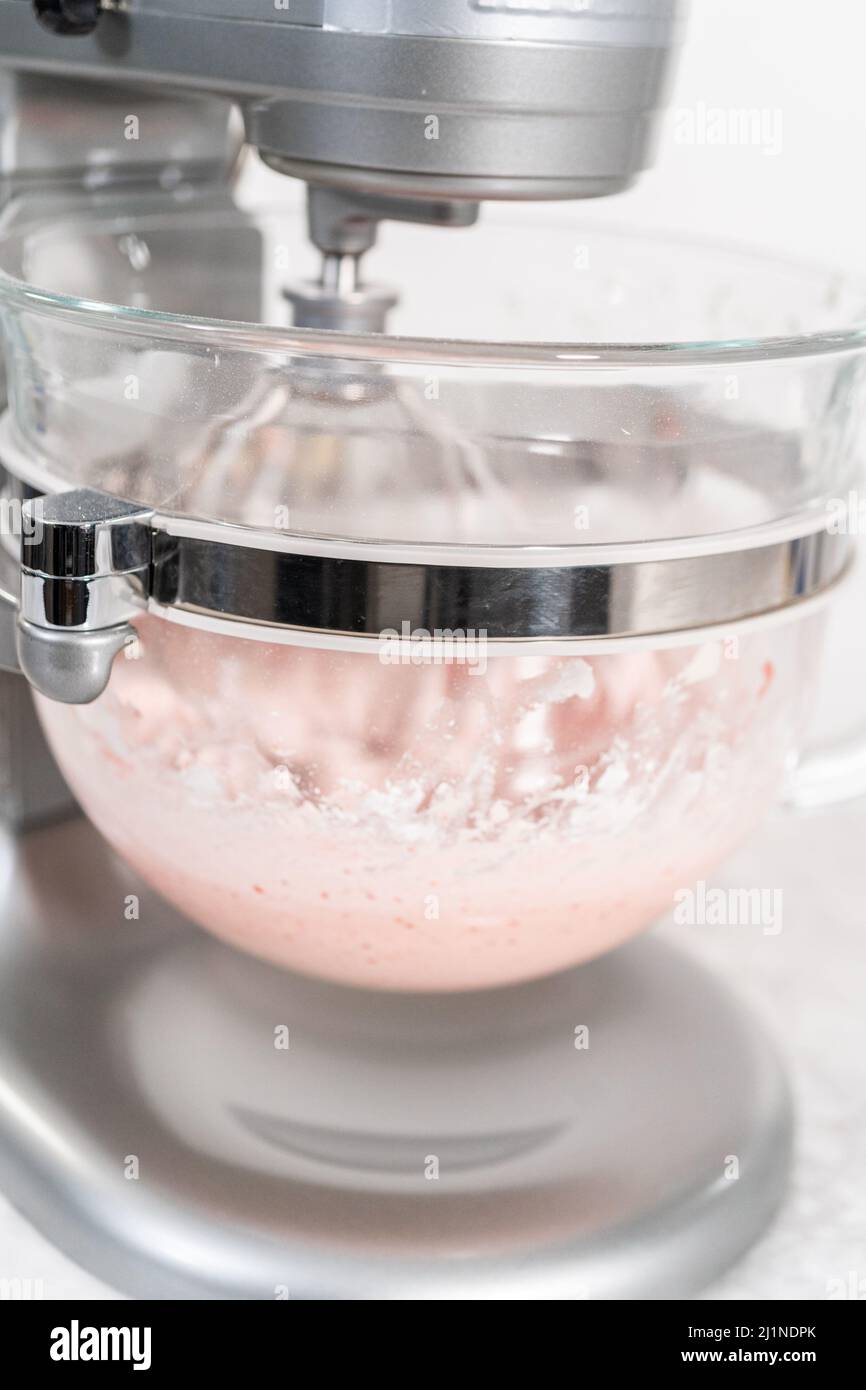 Whipping strawberry buttercream frosting in a standalone electric