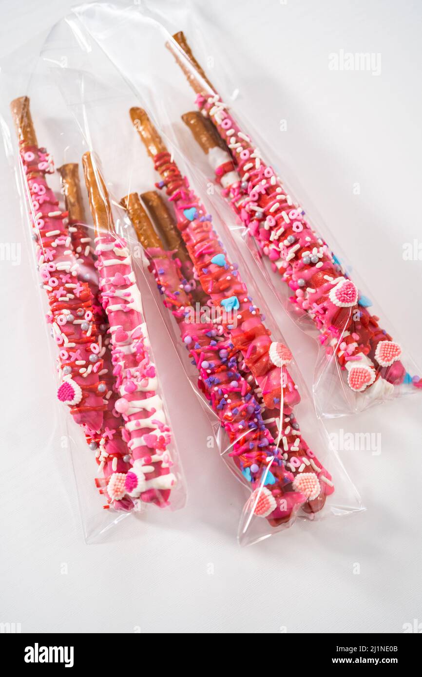 Chocolatecovered pretzel rods decorated with heartshaped sprinkles