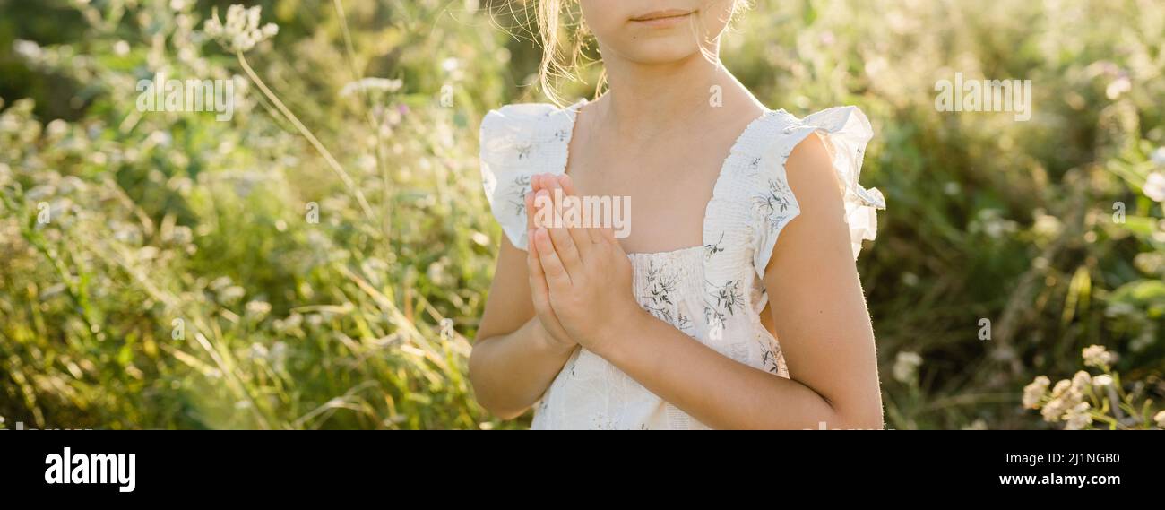 Praying hands of child girl. Photo in the fields Stock Photo