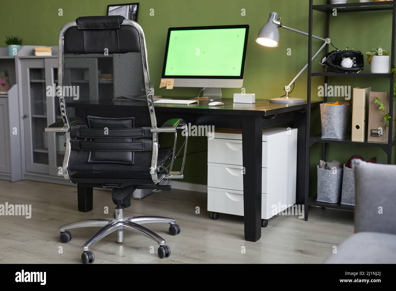 Background image of home office workplace with chroma key computer screen on desk against green wall, copy space Stock Photo