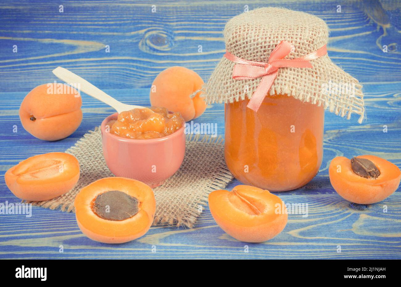Fresh homemade apricot marmalade and ripe fruits on blue boards, concept of healthy sweet dessert Stock Photo