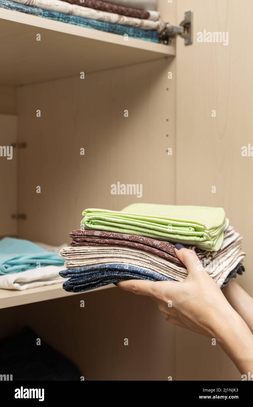 female hands stack folded linen in closet. High quality photo Stock Photo