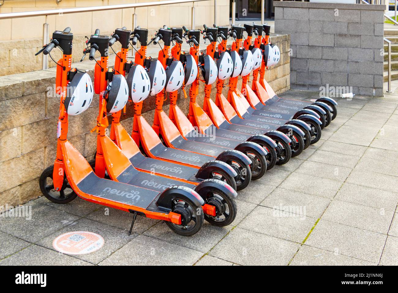 orange Neuron mobility e scooters for hire parked in a row in Newcastle
