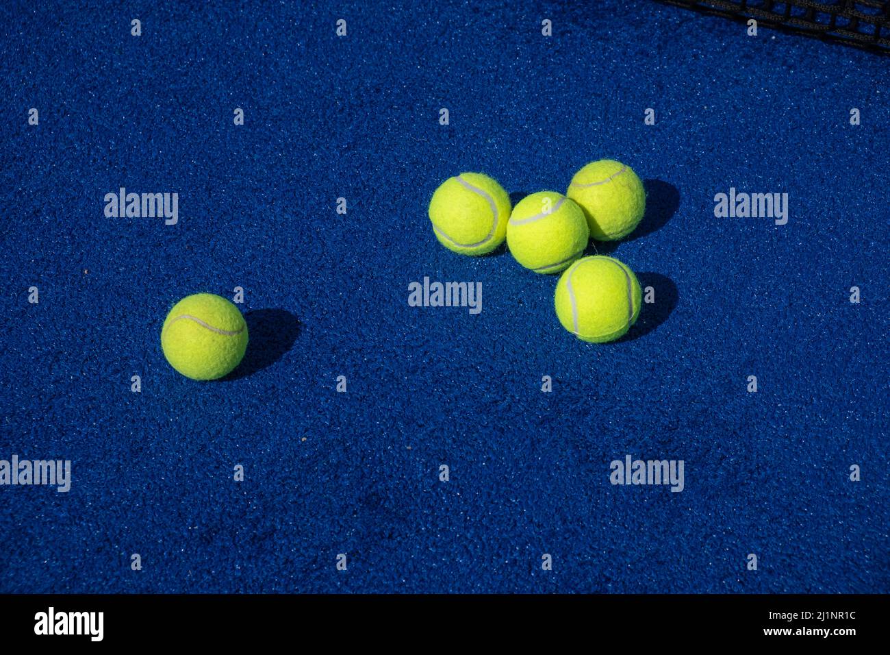 five paddle tennis balls and the net of a blue paddle tennis court, selective focus Stock Photo