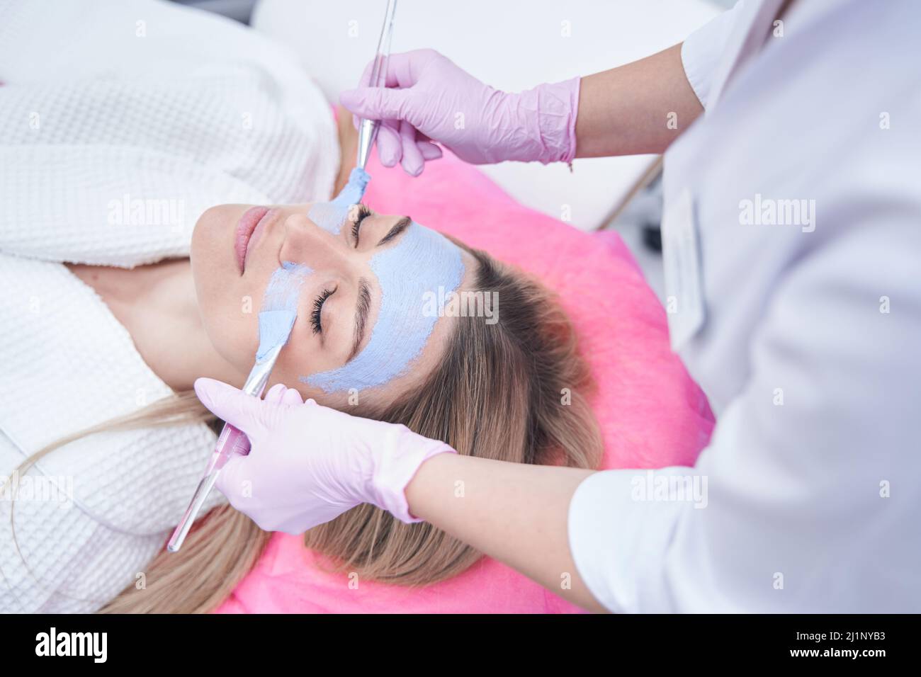 Dermatologist applying mask to face of young woman Stock Photo Alamy