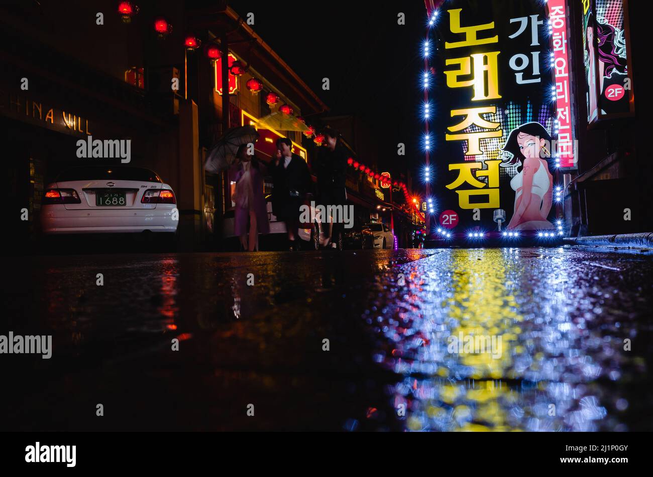 Busan, South Korea - March 19, 2018: Night street view with colorful advertising of Music Bar, people and cars are on the street. Text in Korean means Stock Photo