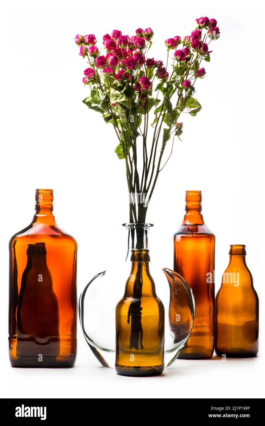 Still life with glass bottles and a bouquet of roses on a white