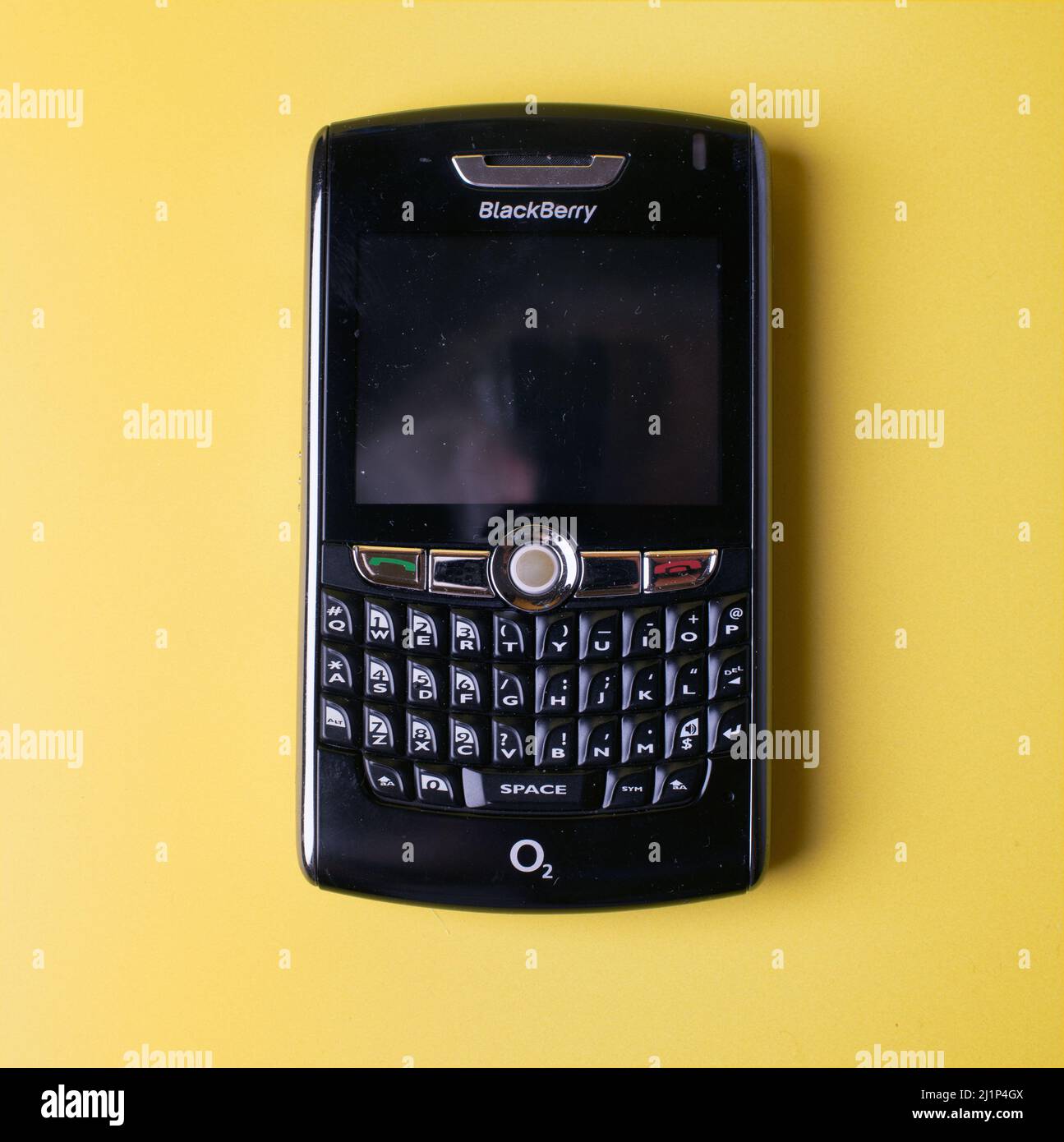 O2 network Blackberry 8800 cell phone personal organiser against a yellow background. Stock Photo