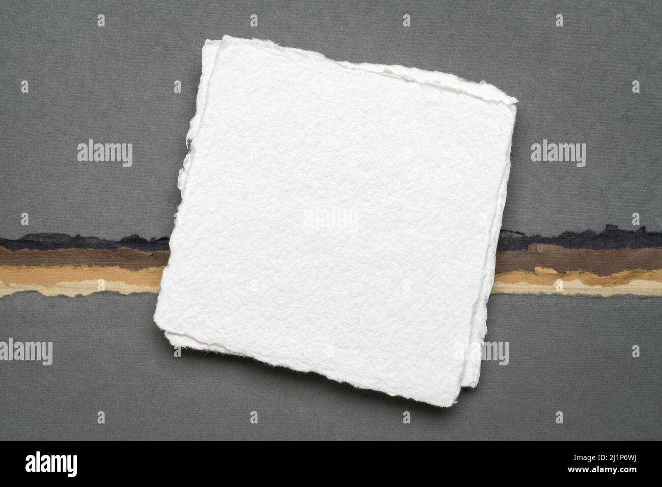 small square sheet of blank white Khadi paper against abstract paper landscape in earth colors Stock Photo