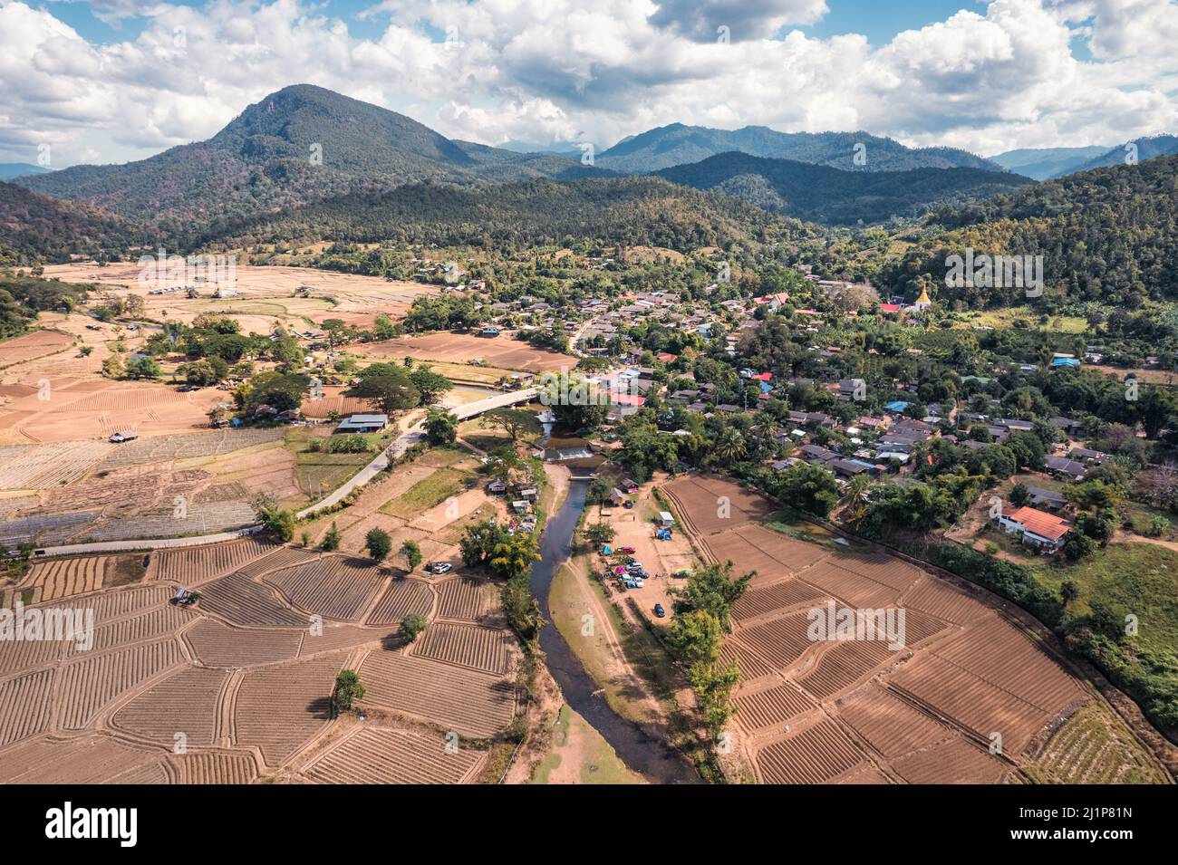 Aerial view of tranquil local village with river flowing through among the valley and rice plantation on dry season in countryside at Muang Kong, Chia Stock Photo