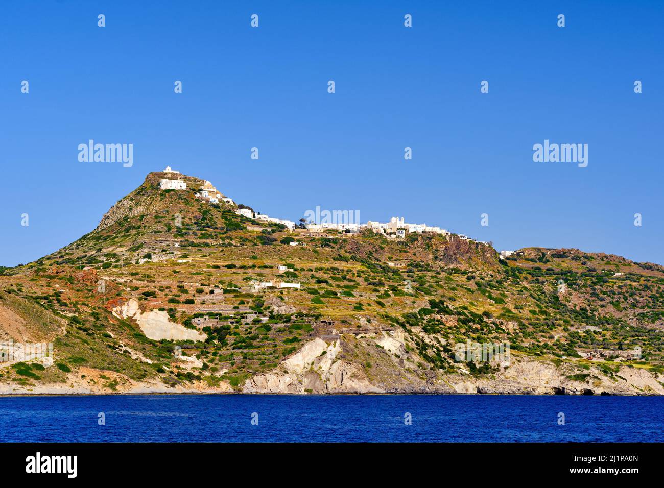 Beautiful view of Mediterranean island. Whitewashed houses atop of high hills, terraced slopes, winding roads, white Orthodox church dominate skyline Stock Photo