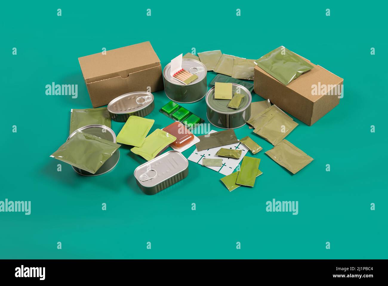 Canned food set and terrines with survival accessories on green background. Stock Photo