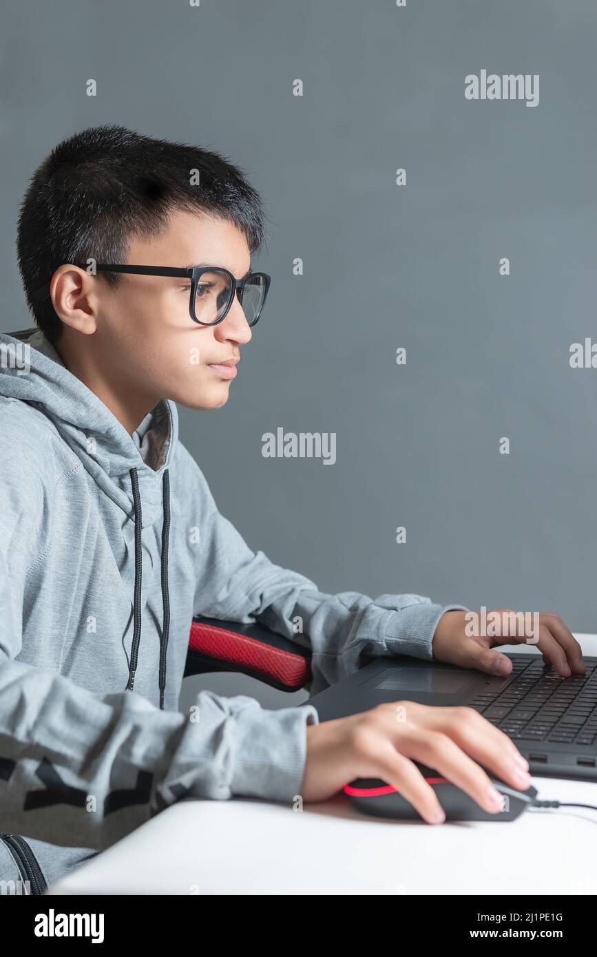 Teen teenager boy home schooling studying room desk PC computer glasses sitting watching homework Stock Photo