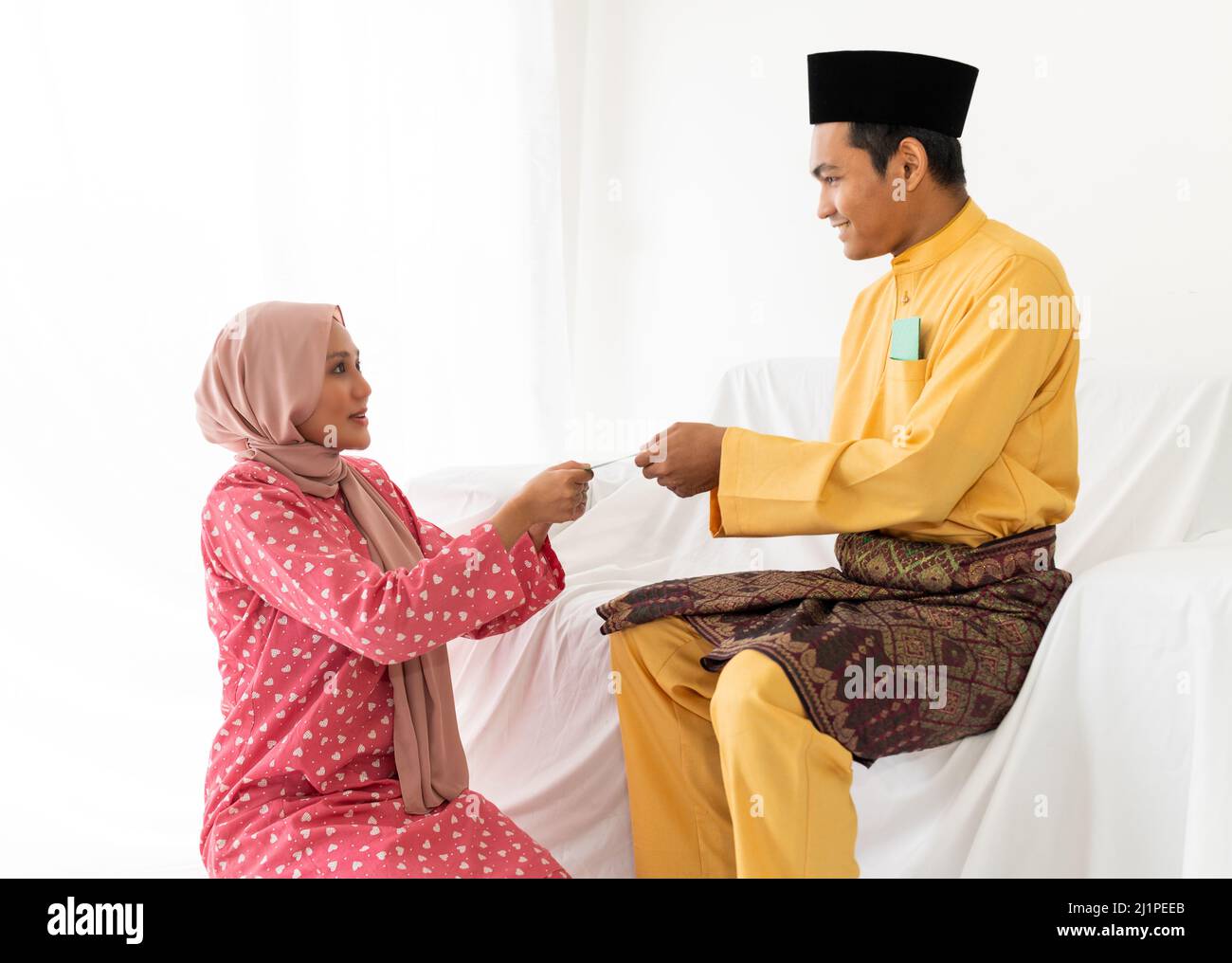 A young Muslim couple celebrates end of Ramadan, the Islamic holy month, by giving money packet, and seeking forgiveness Stock Photo