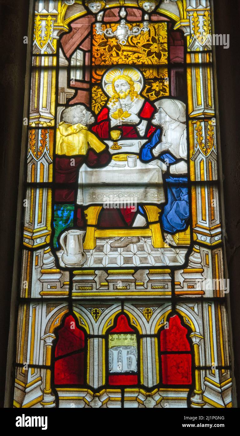 A Victorian stained glass window showing Jesus Christ breaking a loaf of bread with a challice of wine on a table, demonstrating an act of communion. Stock Photo
