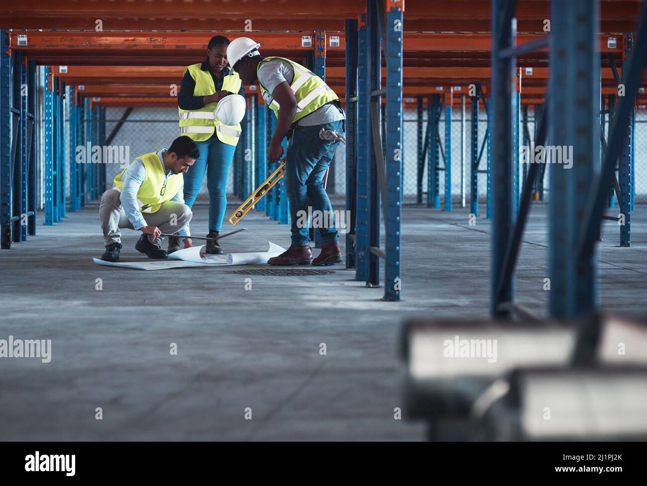We speak engineer fluently. Shot of a group of contractors using a blueprint to plan in the warehouse. Stock Photo