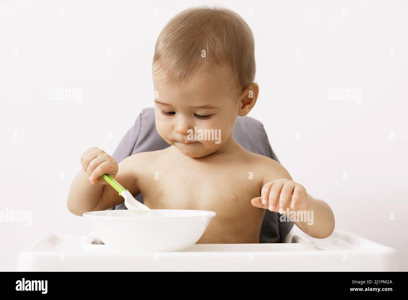 Cute hungry baby sitting in the high chair Stock Photo Alamy