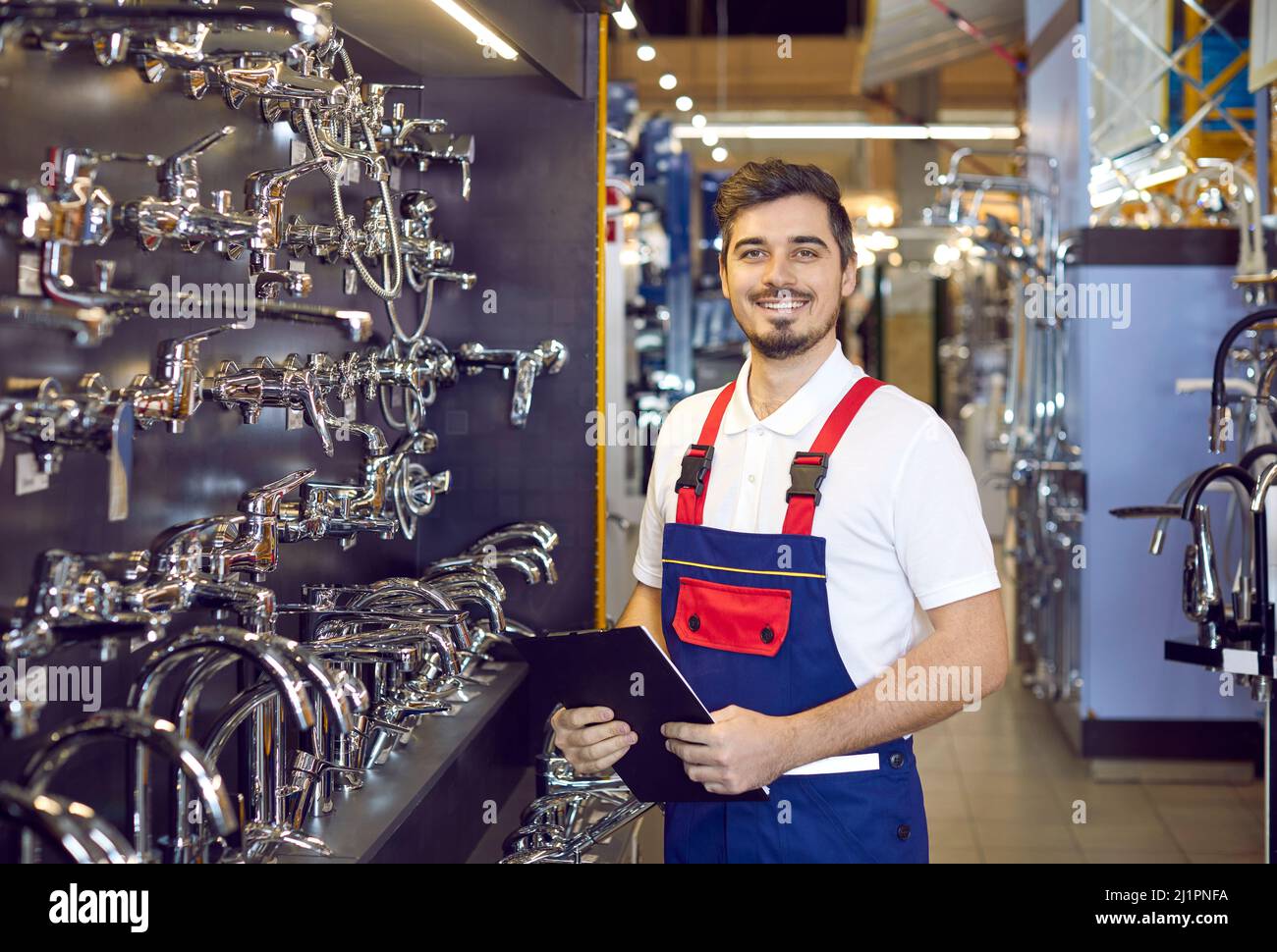 Happy sales assistant in the aisle with water taps at a hardware store