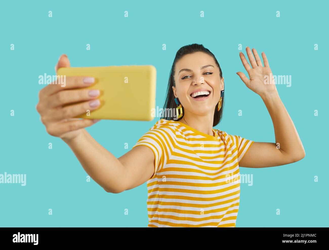 Happy woman taking selfie or making video call on phone, waving hello and smiling Stock Photo