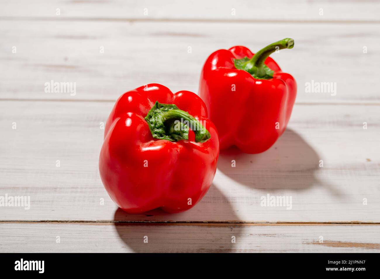 Two red sweet peppers on a wooden background. Light background. Food, vegetarian concept. Stock Photo