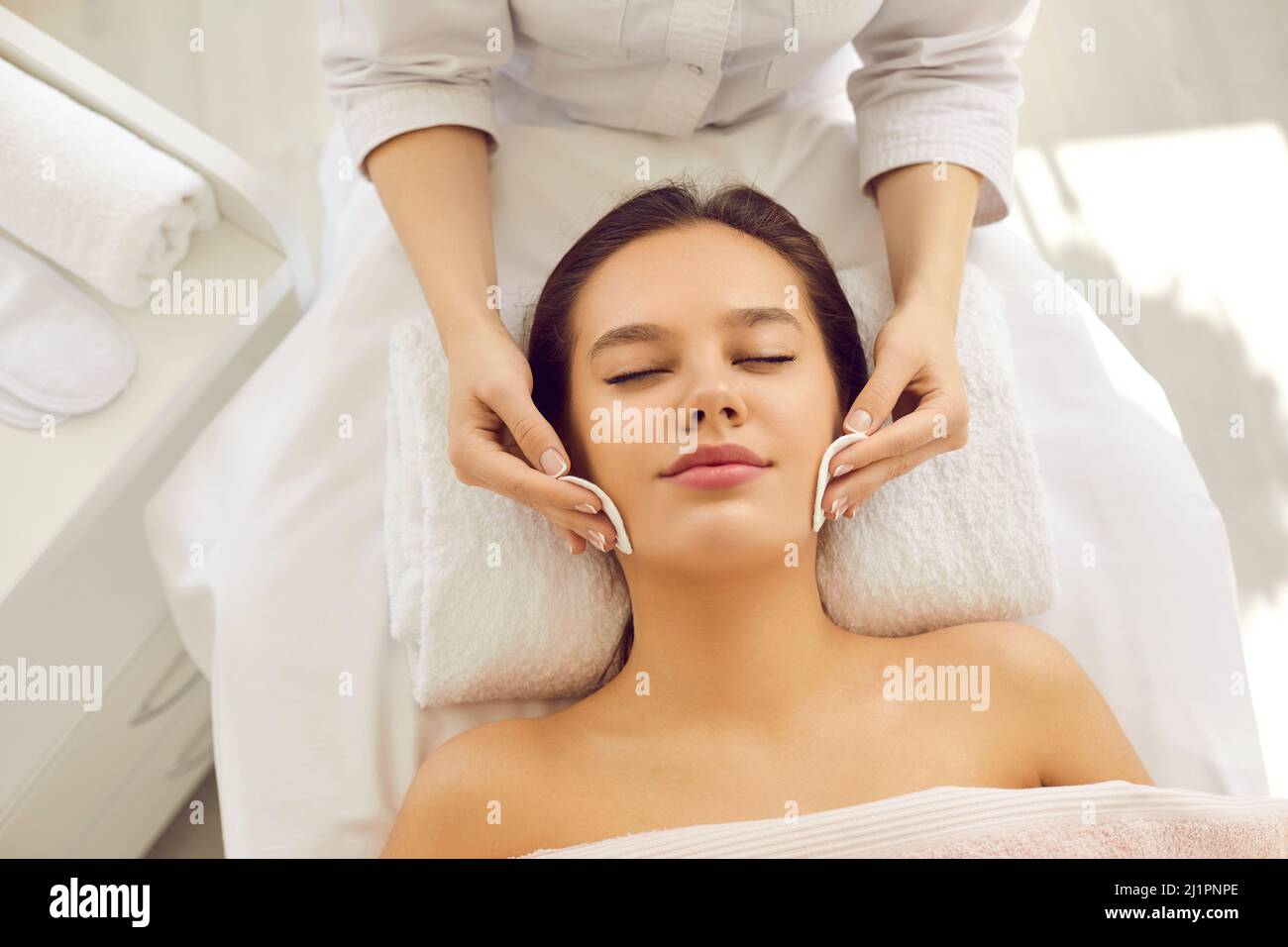 Beautician cleaning skin before facial procedure and removing makeup