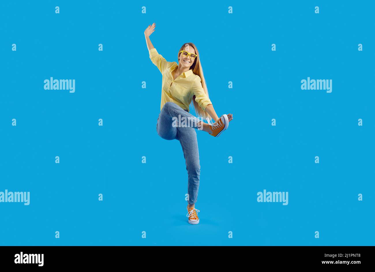 Cheerful crazy young woman having fun showing funny movements on light blue background. Stock Photo