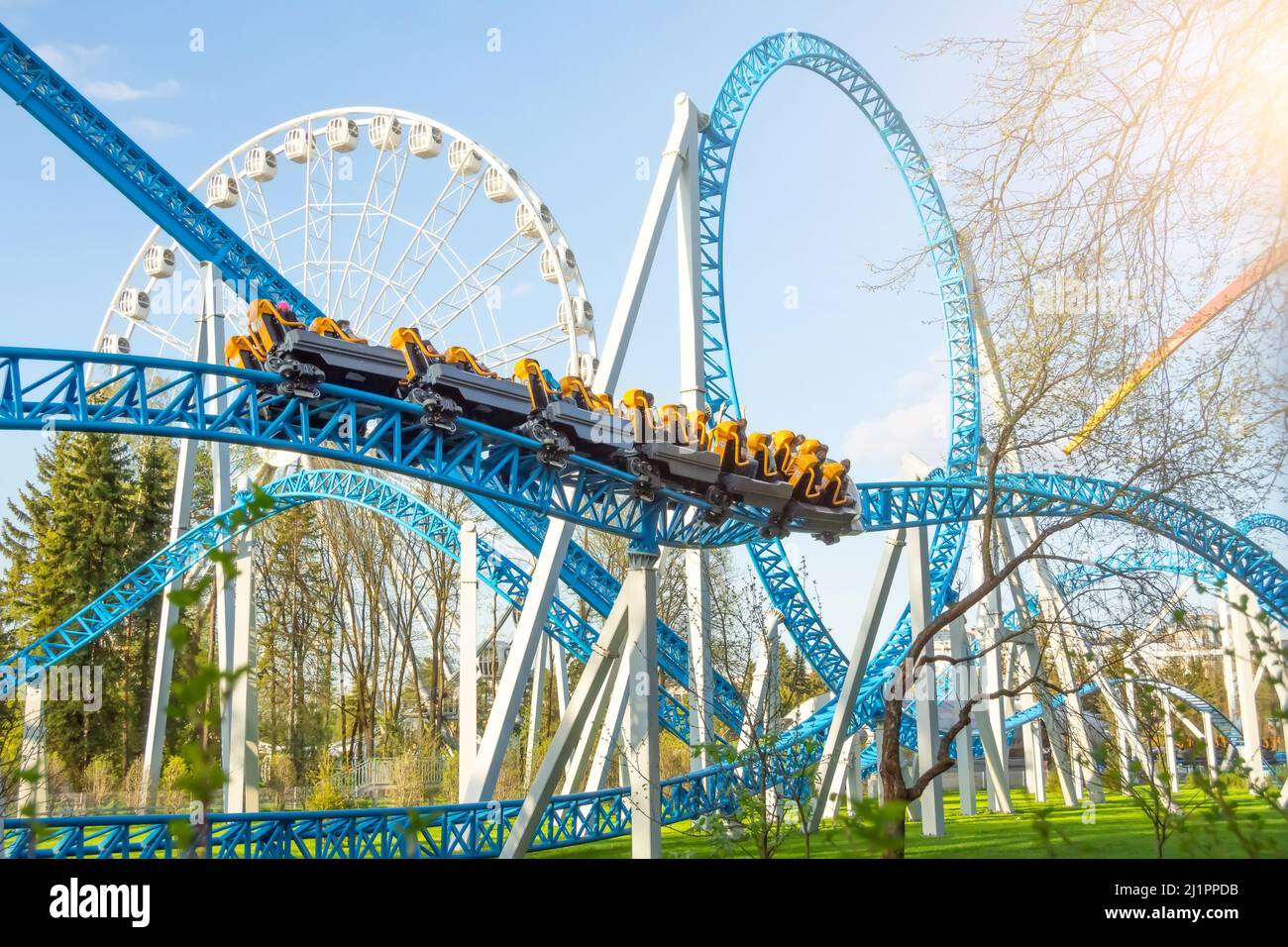 Amusement trolley makes circle loop turns rides in a spiral, roller coaster.  Ferris wheel in the background Stock Photo - Alamy