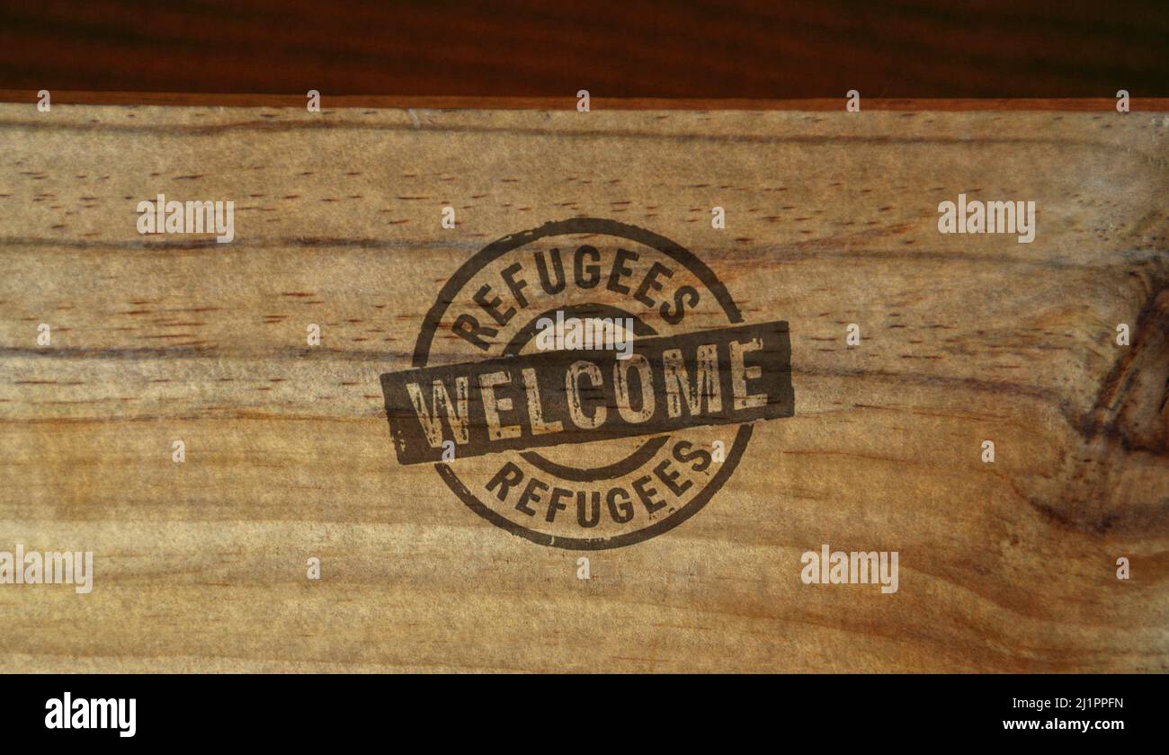 Refugees Welcome stamp printed on wooden box. Migration and humanitarian aid during the crisis concept. Stock Photo