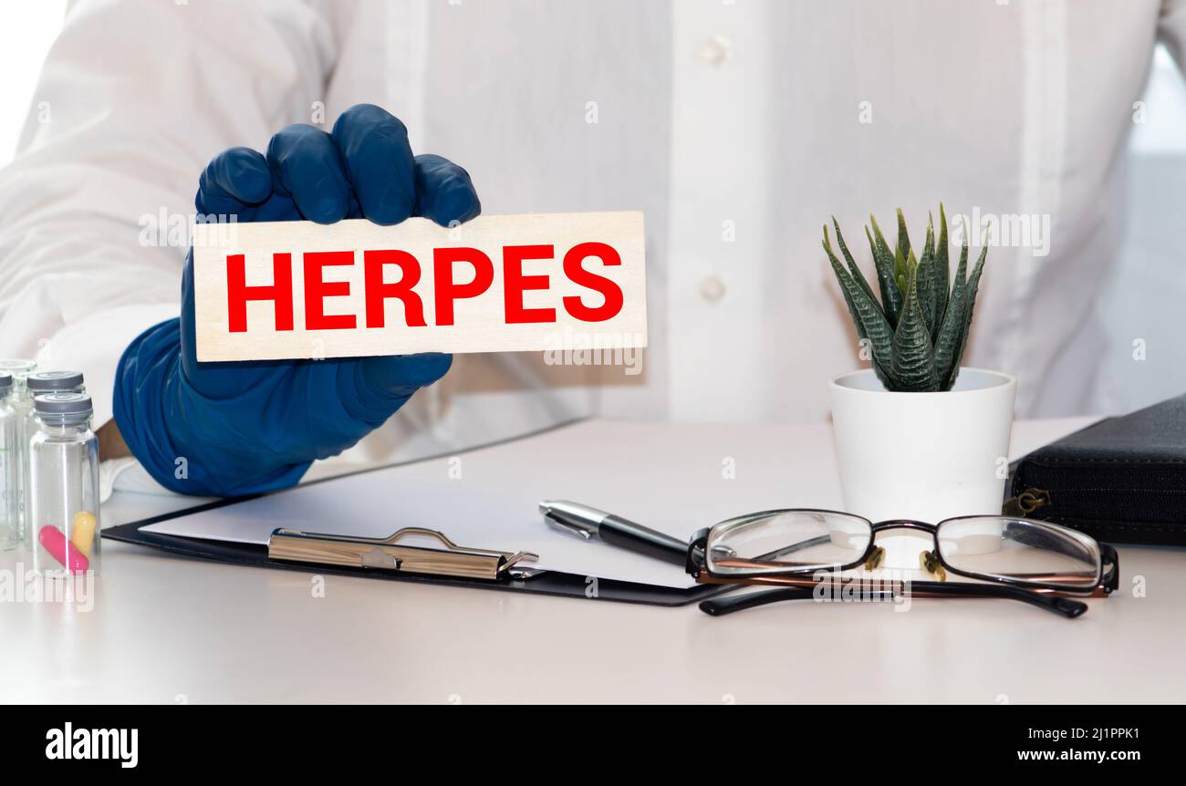 Female doctor holding a tablet with the text: Herpes. Stock Photo